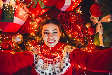 Joyful christmas moment a woman in a red sweater smiles among twinkling lights gifts and decorations at home