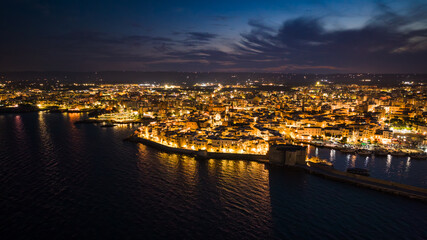 Night view of the illuminated old town, port and castle in Monopoli, Italy, from above