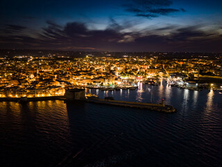 Iconic view of the illuminated historic center, harbor, and castle of Monopoli, Italy, at night