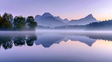 Obraz premium A lake surrounded by mountains and shrouded in fog, with trees visible in the foreground