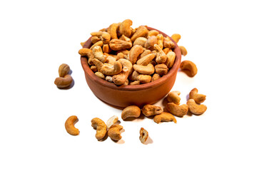 Roasted cashew nuts in clay bowl on white background