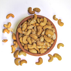 Roasted cashew nuts in clay bowl on white background