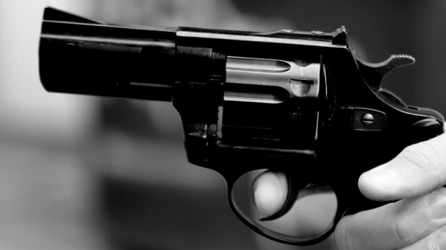 Close-up of a pistol in a hand pulling the trigger and firing a shot