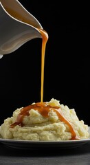 A rich brown gravy being poured dramatically over a mountain of creamy mashed potatoes during a festive holiday family feast, seasonal, brown, dinner
