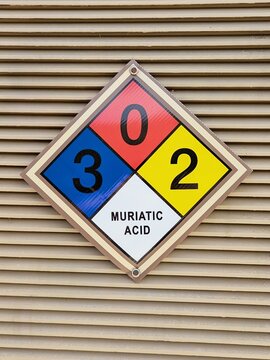 Diamond shaped NFPA panel identifying hazardous at public pool. Muriatic acid