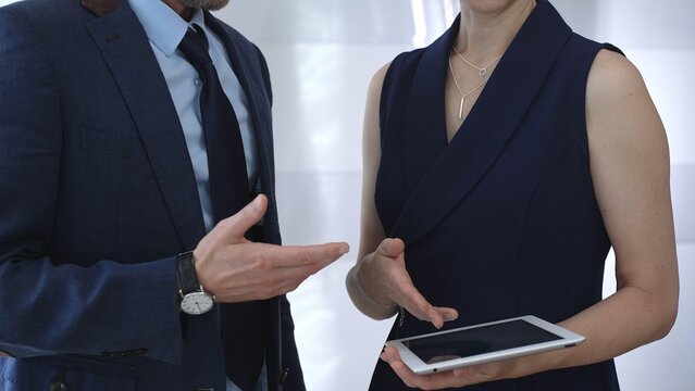 Business colleagues collaborating, discussing strategies, and sharing insights while presenting information on a digital tablet during a professional meeting - Powered by Adobe