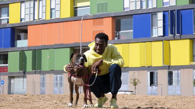 African american man petting his dog in a colorful neighborhood