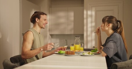 A couple shares a delightful breakfast of fresh food and drinks in their bright, modern kitchen - Powered by Adobe
