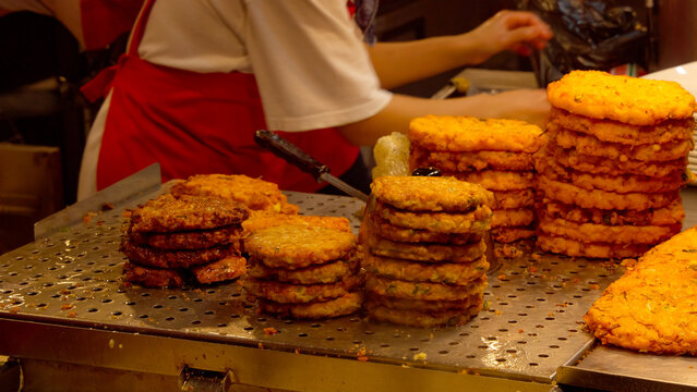 Vendor preparing and stacking hot fried Korean mung bean pancakes at a traditional street market