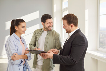 Real estate agent and overjoyed loving couple signing documents moving new flat, family relocation...