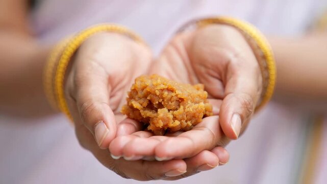 Prasad Offering During Indian Festival Celebration, Hands Holding Sweet, Traditional Cultural Ritual, Religious Event, Spiritual Practice, Sacred Gift, Devotional Act, Cultural Significance