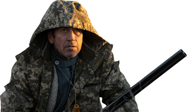 Mature man hunter with gun looking out for a flock of birds.