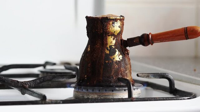 Coffee boiling over from turk and extinguishing gas stove flame during cooking process