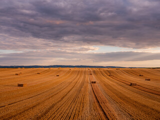 Obraz premium Harvested field with hay bales under dramatic sky