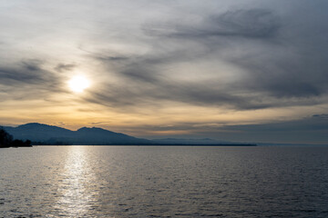 sunset in clouds over Lake Constance Bodensee with blue water, dark clouds and cloudy sky with negative space for text