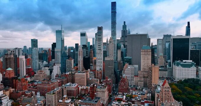 Multi-storied buildings and skyscrapers of amazing New York, USA. Approaching the beautiful greenery of Central Park. Dramatic cloudscape covering the sky over the city.