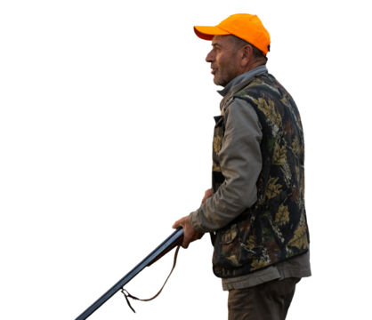 Mature man hunter with gun while walking on field.