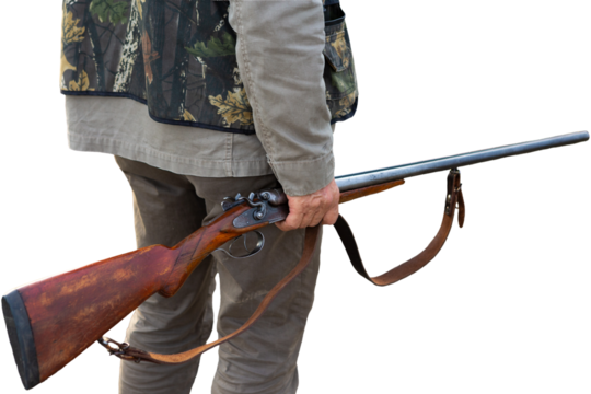 Mature man hunter with gun while walking on field.