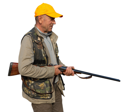 Mature man hunter with gun while walking on field.