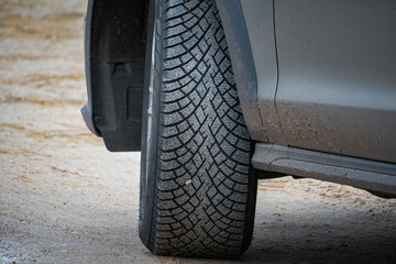 Close-up of car tire with detailed tread pattern on dirt road, concept of transportation, safety,...