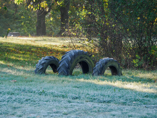 Three tractor tires half-buried in the lawn with morning frost.
