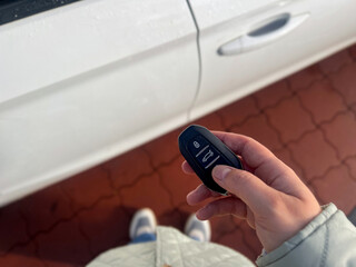 Close up of a female hand holding a car key and unlock the car