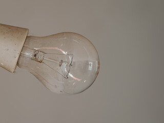 A non-illuminated filament bulb in a white socket with a white background.
