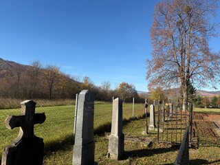 Old rural cemetery in autumn with gravestones and a field under a clear blue sky