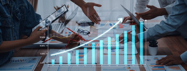 Diverse team working together in a professional setting, analyzing charts and graphs for growth strategy while using digital devices on the table. Scalp