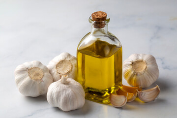 Ripe and raw garlic and garlic oil in glass of bottle on wooden table with burlap sack, alternative medicine, organic cleaner.