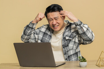 Displeased Asian Chinese man using laptop notebook typing working, loses becoming surprised sudden...