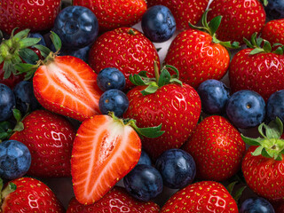 Obraz premium Close up view of fresh strawberries and blueberries mixed together, healthy fruit diet, summer freshness concept