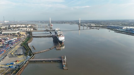 Aerial drone view of Queen Elizabeth bridge and large cargo ships docked on the river Thames in Dartford at sunset, UK