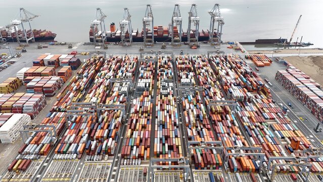 Aerial drone shot of large cargo ship tanker, gantry cranes and shipping containers being loaded and unloaded at London gateway port, River Thames UK