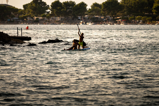 Children having fun on the paddle board at the Cres island, Croatia, during summer sunset