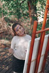 Obraz premium Little girl painting outdoors in a forest setting