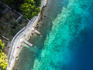 Top down aerial view of beautiful, secluded beach in the small bay of Cres island, Croatia, with beatiful, turquoise sea splashing the sand shore