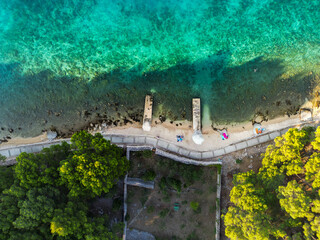 Top down aerial view of beautiful, secluded beach in the small bay of Cres island, Croatia, with beatiful, turquoise sea splashing the sand shore