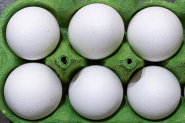 Fresh white eggs in a green carton ready for cooking or baking in a kitchen setting