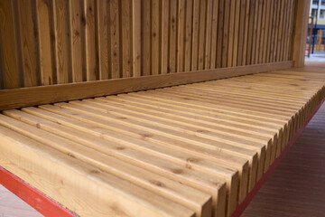 Wooden bench outdoors, Outdoor wooden bench with metal accents, Comfortable timber seating on urban plaza, Charming outdoor bench featuring red supports and warm wooden