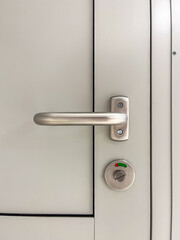 Modern door handle with sleek metallic finish and circular lock mechanism, showcasing minimalist design and functionality in contemporary architecture