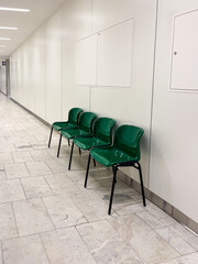 Modern hospital corridor featuring clean, spacious design with green chairs arranged neatly, creating a welcoming atmosphere for patients and visitors in a well-lit environment