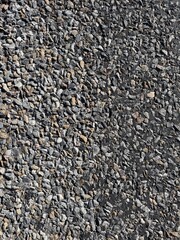 Close-up of asphalt surface with visible gravel stones and natural rough texture. Neutral Gray tones, high detail, and realistic pattern make it perfect for backgrounds, design projects, and architect