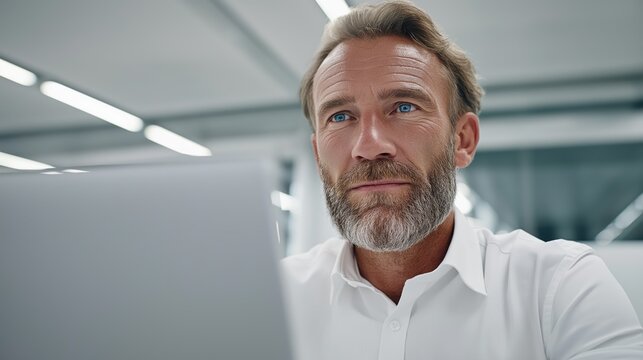 Busy caucasian male bank manager focused on laptop while analyzing financial report in modern office environment - Powered by Adobe