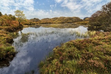 A cloudy, calm Scottish autumn day at Black Loch with lovely reflections in Lairg, UK