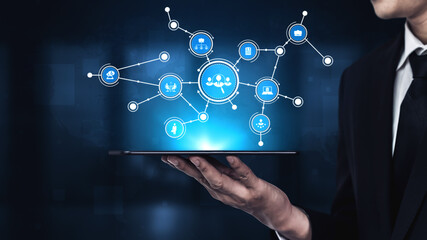 Business professional displays a tablet showcasing digital network symbols and icons. This image represents innovation, connectivity, and modern technology in a professional workspace. Tessel
