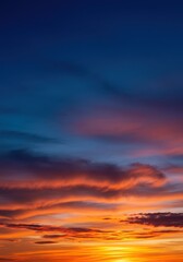 Fototapeta premium Vibrant summer sunset with clouds illuminated in orange and pink against a deep blue sky transitioning from day to night ,wide ,dusk ,soft
