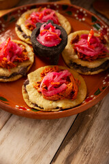 Panuchos, a typical dish from Yucatan, Mexico. A handmade, fried corn tortilla filled with beans, topped with cochinita pibil, pickled red onion, and habanero pepper.