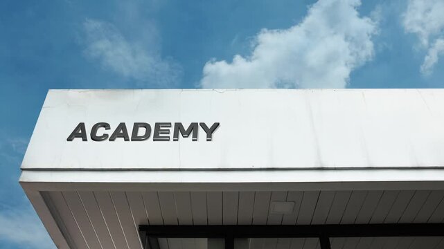 Bold Academy word sign displayed prominently on a stately institutional building, set against a bright, clear blue sky. Perfect for excellence, training, and specialized education themes