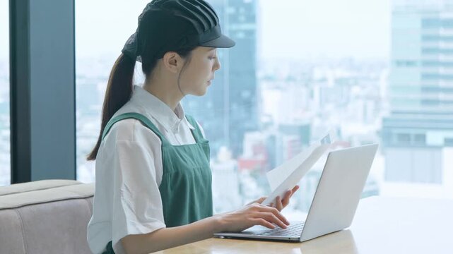 グラフ・売り上げを見てパソコンに打ち込む女性